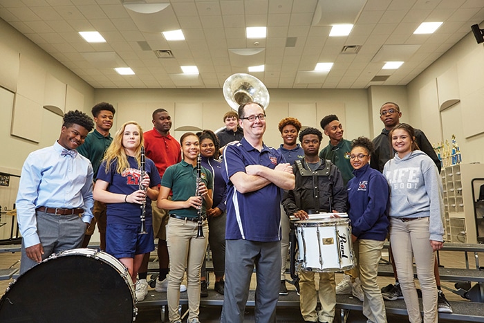 Skip Redd in music room surrounded by students with musical instruments.