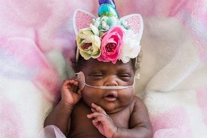 Baby in the NICU wears a unicorn hat with a flower crown.