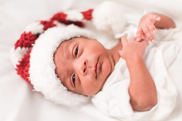 Baby in the NICU wears a crochet Christmas stocking hat.