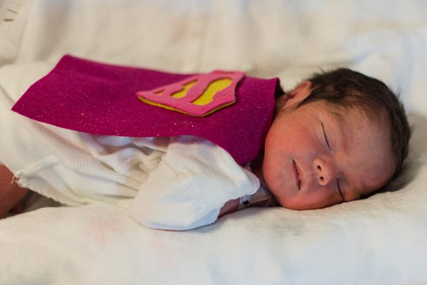 Baby in the NICU wears a crochet Superman cape.