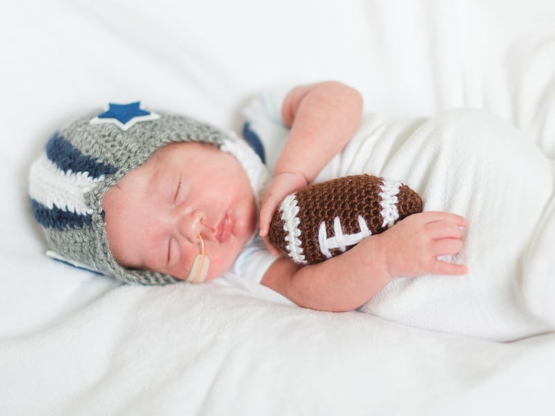 NICU baby wears a crochet football helmet.