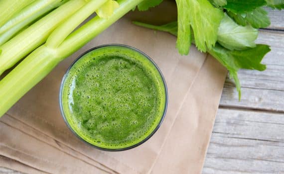 Glass of celery juice, a health trend debunked, with stalks of celery