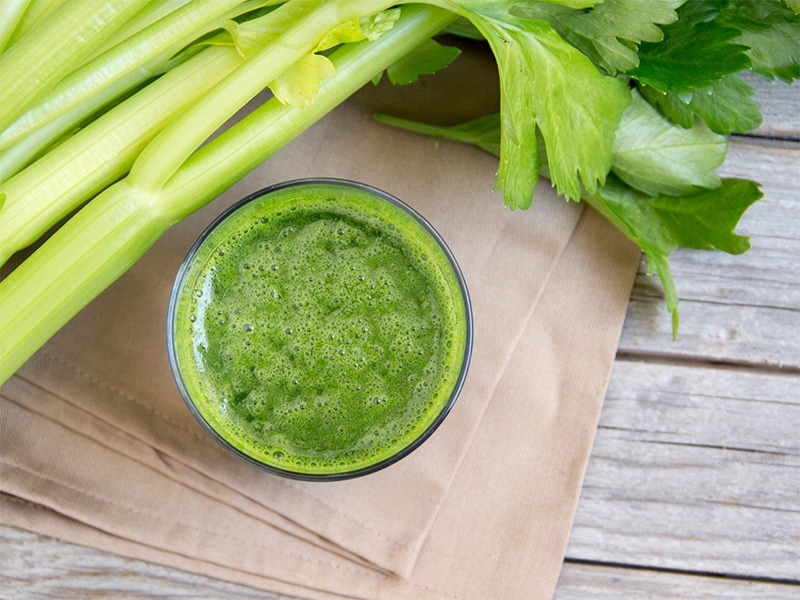 Glass of celery juice, a health trend debunked, with stalks of celery