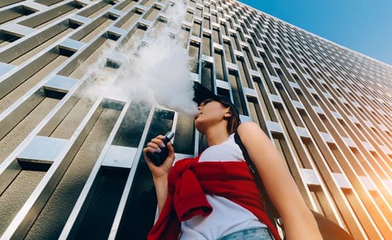 Woman outside a building vaping.