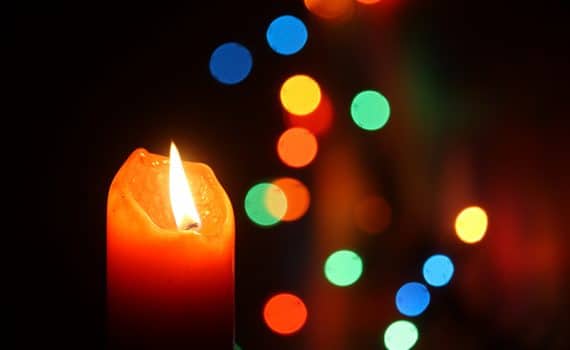 Candle with Christmas decorations; learn about holiday mental health.