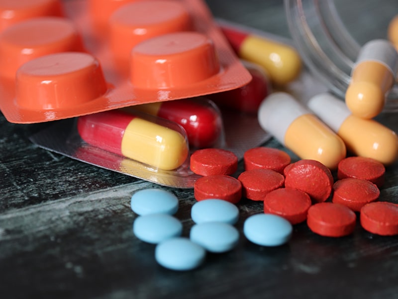 Medication and prescription pills gathered on table, used to explain COVID-19 remedies