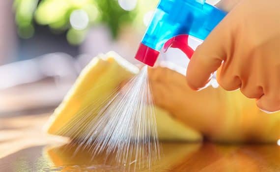 Person spraying cleaner and wiping with rag, cleaning surfaces in the home that may have germs
