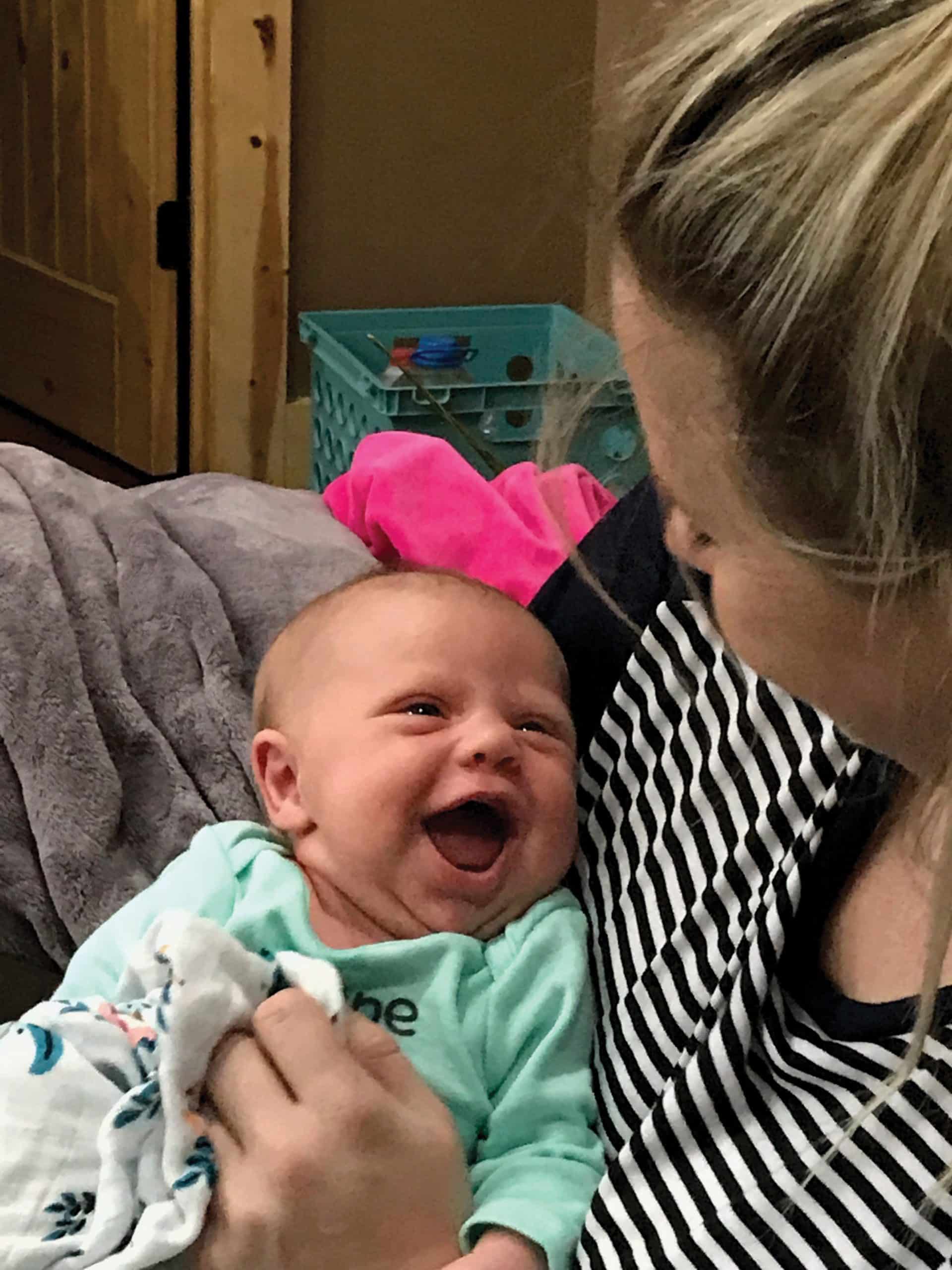 Whitney Monroe, weight-loss surgery patient, holds her newborn Anika, who looks up at her and smiles. 