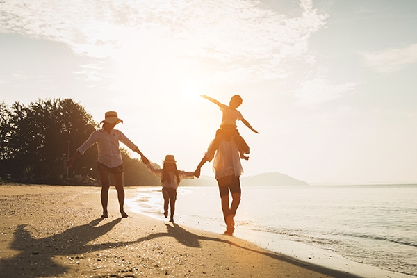 Two adults and two children walking on the beach together during the golden hour