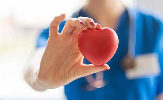 Hospital staff member holding heart object, used to explain stress and COVID-19