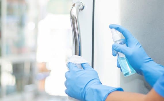 sanitizer spray cleaning a surface by a person wearing blue gloves, used to explain the coronavirus and germs in 2020