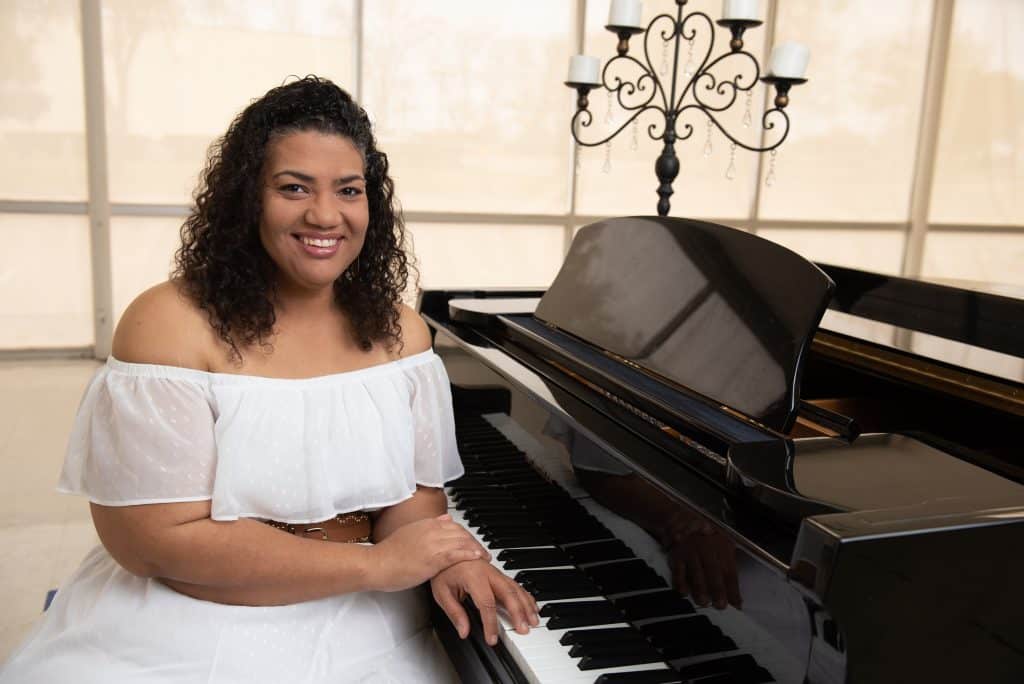 Deanna Lariz smiling in front of her piano