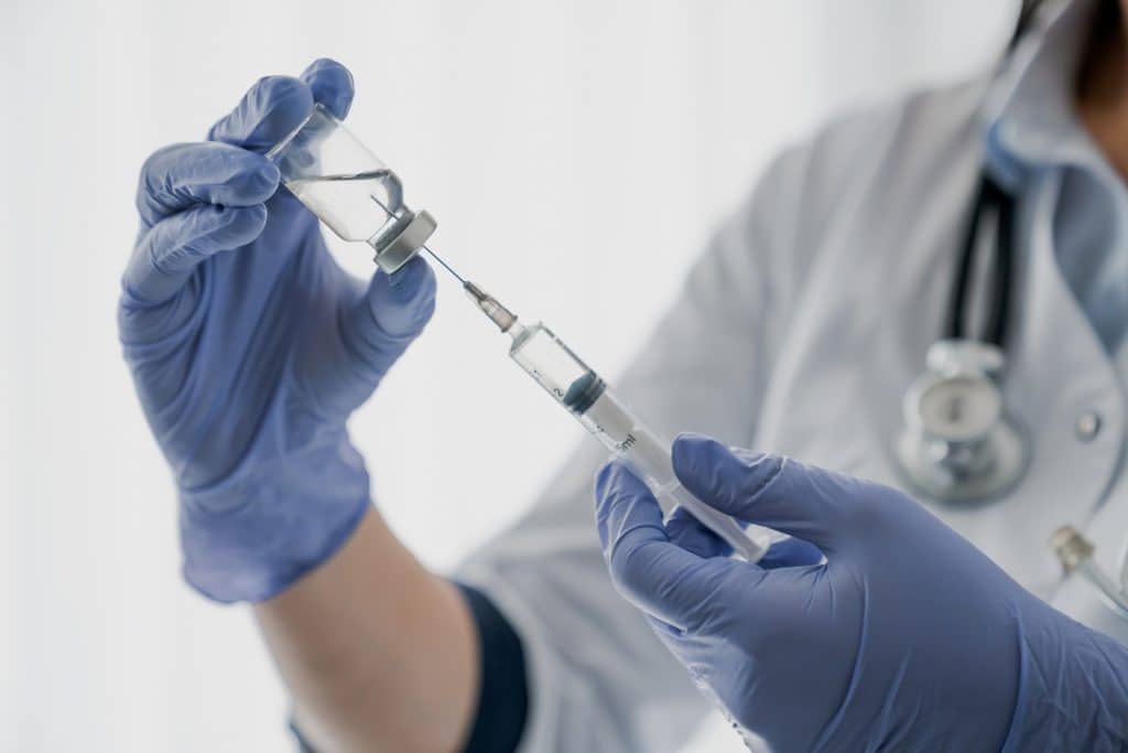 Medical professional wearing gloves and filling a syringe with medication
