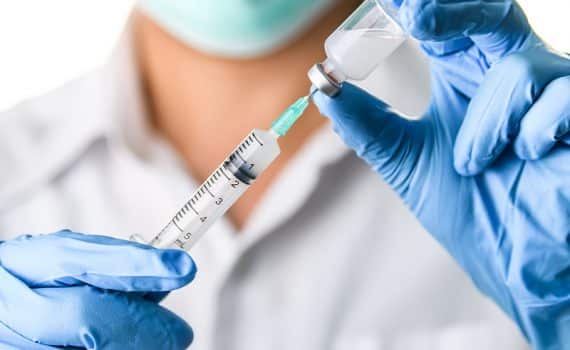 Medical professional wearing blue latex gloves and preparing vaccines