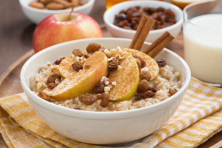 Bowl of high fiber oatmeal and sliced apples with nuts and cinnamon
