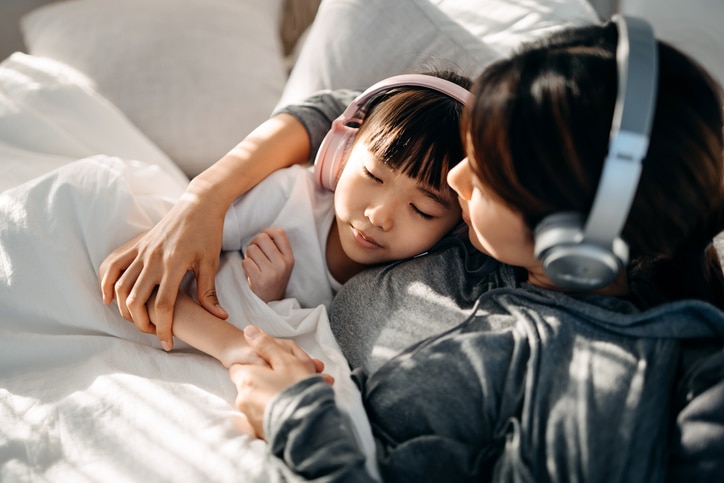 An adult and child listening to headphones and embracing