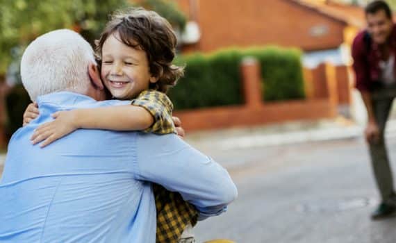 An older man and child hugging, used to explain what actions are safe after getting vaccinated for COVID-19