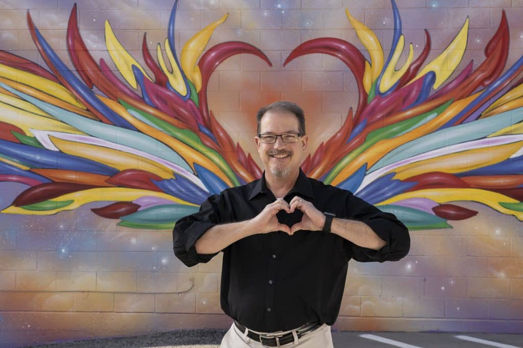 Chuck Roe standing in front of a heart mural in downtown Mansfield, Texas