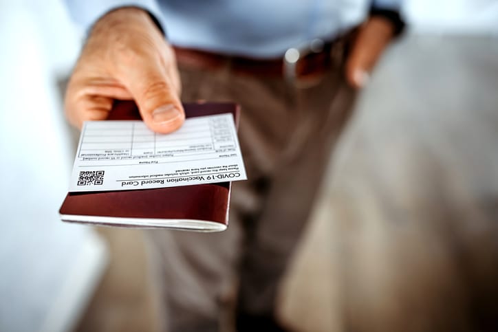 A person holding their COVID-19 vaccination card along with other identifying paperwork