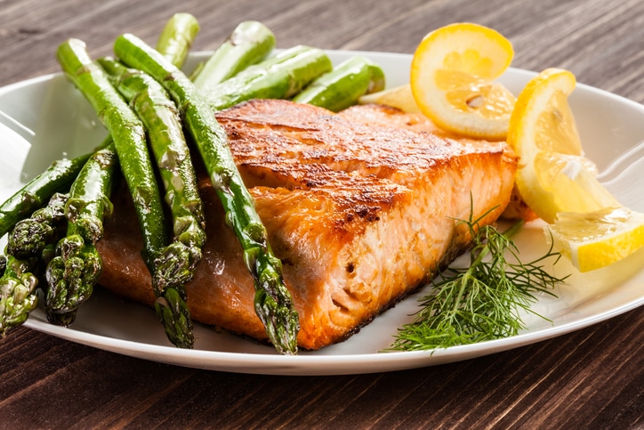 Prepared dinner of salmon, asparagus, dill and lemon on a dinner plate