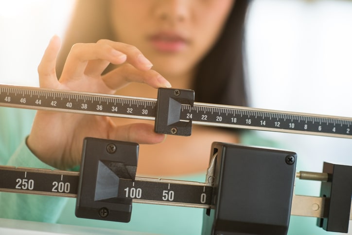 Woman sliding a scale to measure her weight