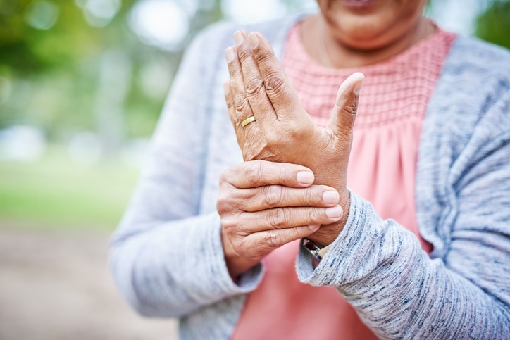 Woman in a gray cardigan rubbing her hands and wrists