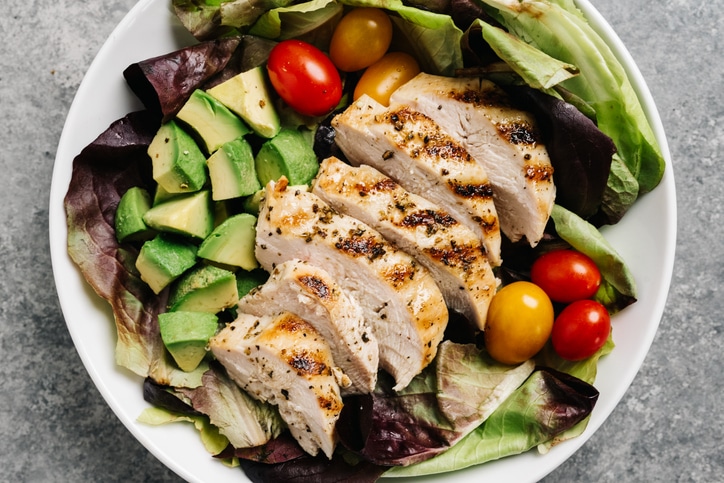 A photo of a salad with grilled chicken, avocado, lettuce, and baby tomatoes