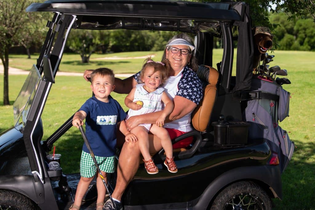 Mimi Leasor on a golf cart with two of her grandchildren