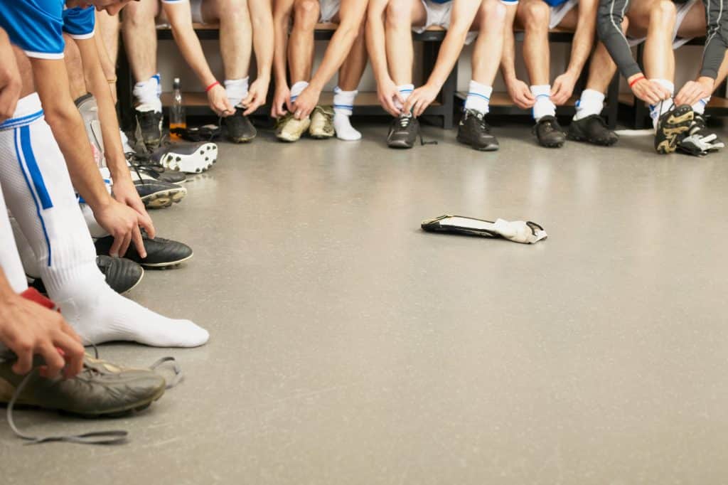 A group of people in a locker room lacing up athletic shoes and putting on socks