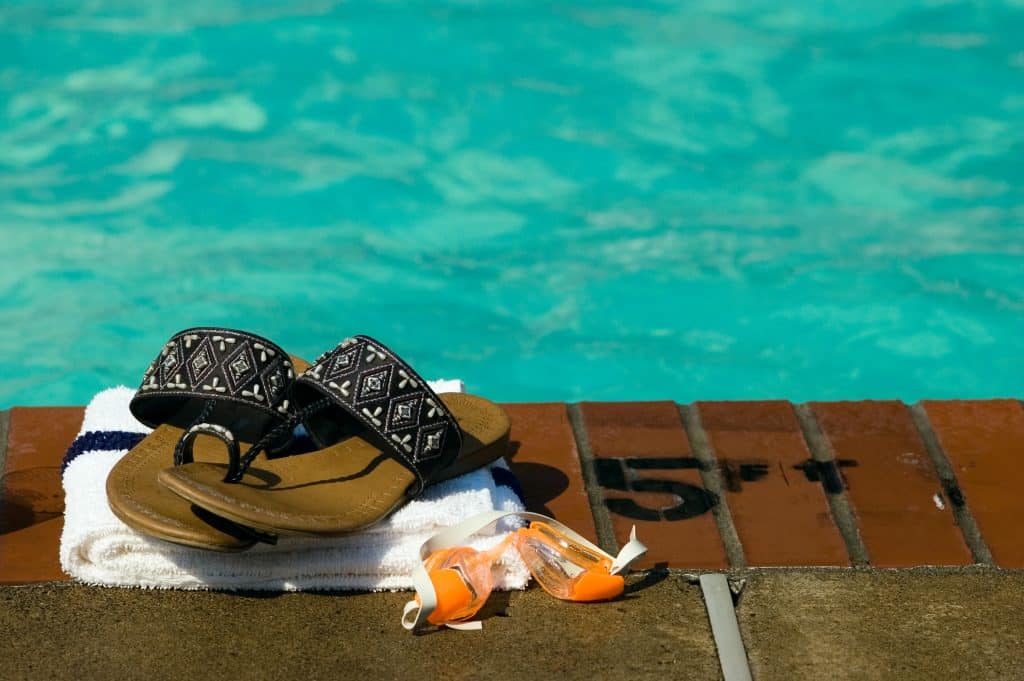 A set of sandals, goggles, and a towel sitting pool-side