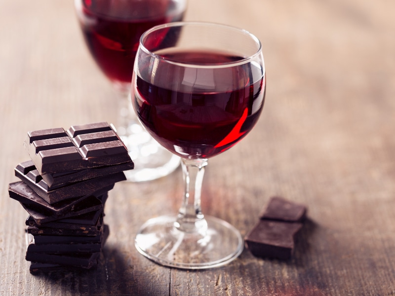 Red wine in glasses with pieces of chocolate bars, used to explain the sirtfood diet