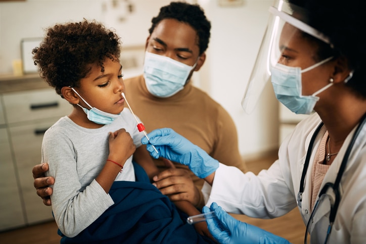 A child receiving a COVID-19 nose swab test with a parent present