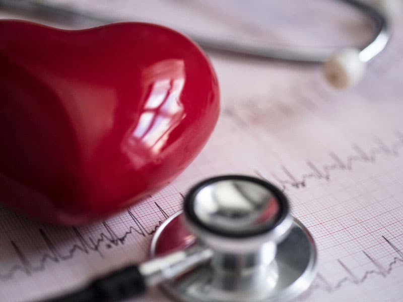 A red heart paper weigh resting on top of papers with a stethoscope near by, used to explain reversing heart disease