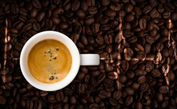 An EKG is superimposed over coffee beans and a cup full of coffee