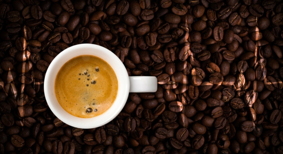 An EKG is superimposed over coffee beans and a cup full of coffee