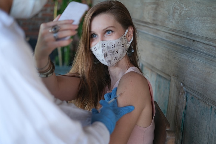 A woman taking a selfie while she receives a vaccine