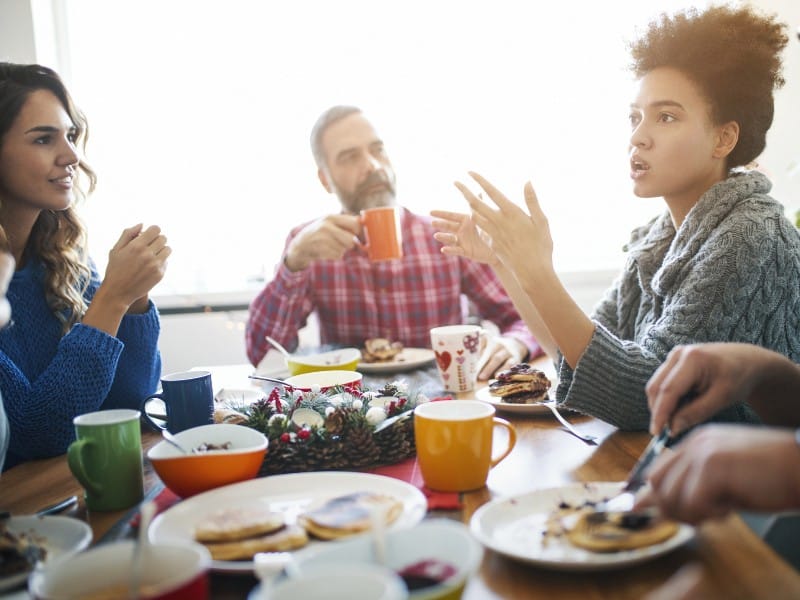 A group of people engaged in a discussion around a dining table