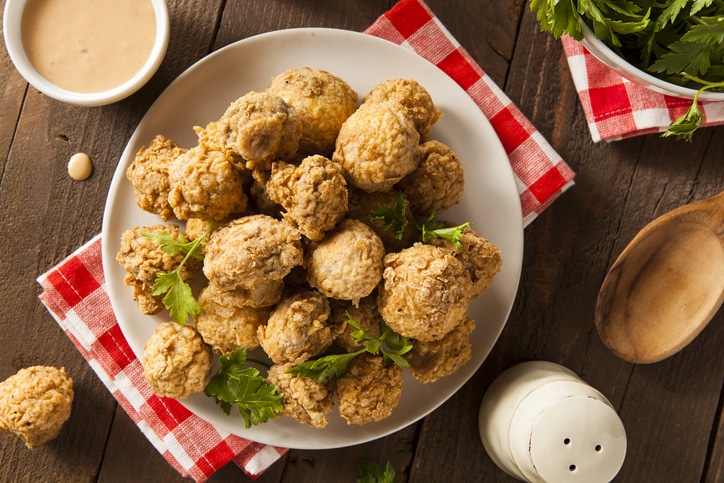 Photograph of fried mushrooms garnished with parsley on a plate and napkin