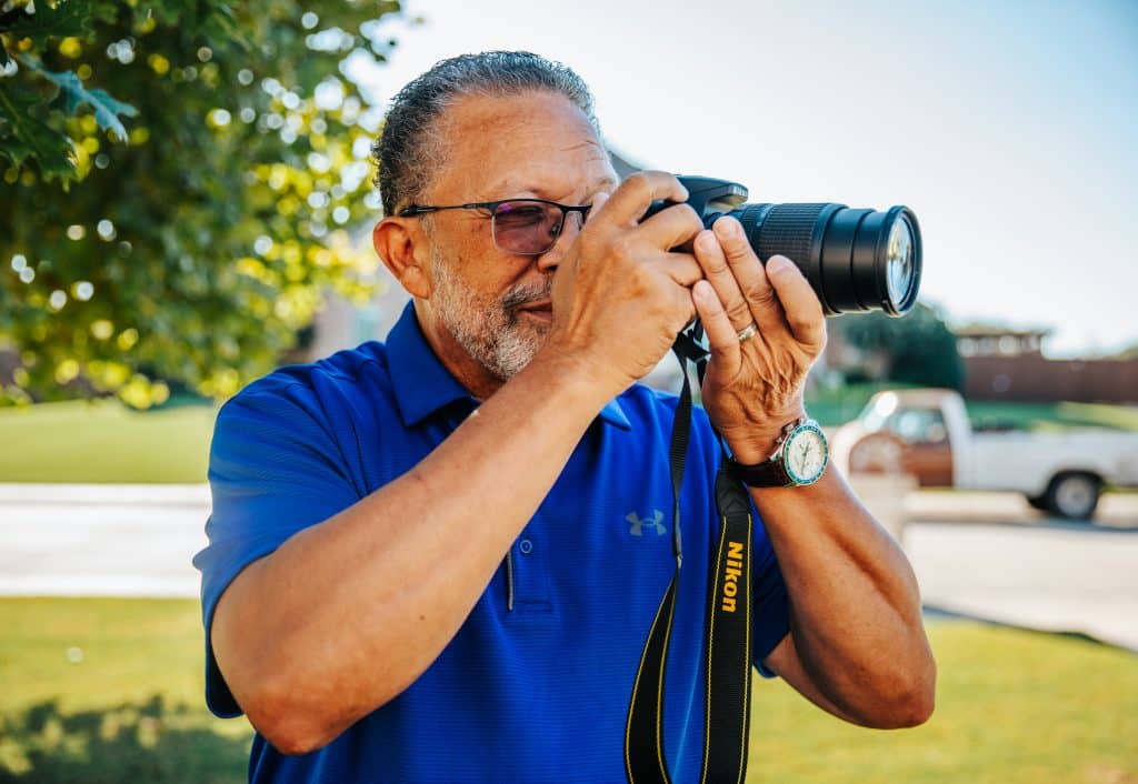 Leonard Jones holding a camera to his face and shooting a photograph