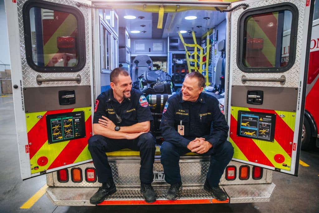 Paramedic and EMS operations manager Michael Marsh and Andrew Armstrong sit in the back of an ambulance
