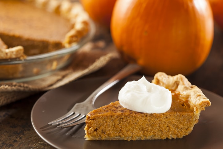 A slice of pumpkin pie with whipped topping and a fork
