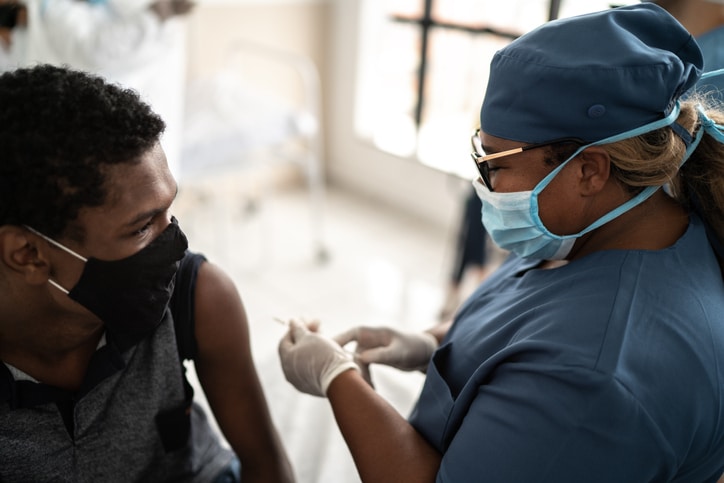 Medical professional preparing a shot for a patient wearing a mask