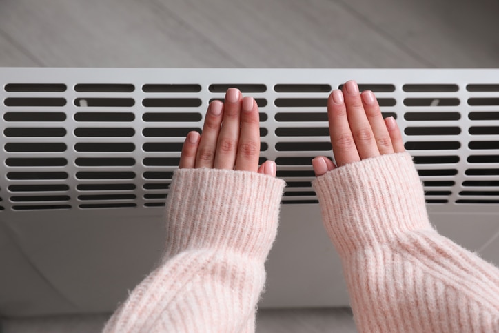 A person's arms and hands extended toward a heater