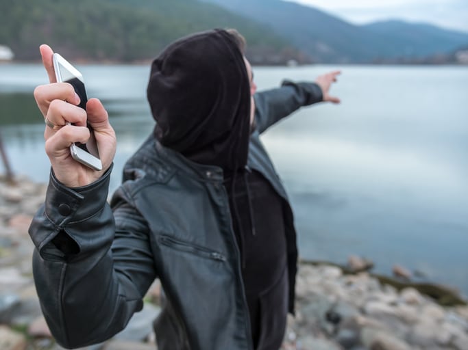 Someone in mid-throw looking like he's going to thrust his phone into a lake in the background