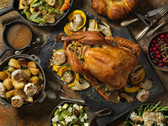 A traditional thanksgiving dinner with a roasted turkey in the middle of the spread