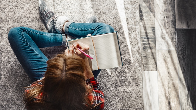 A woman reading and writing in a journal