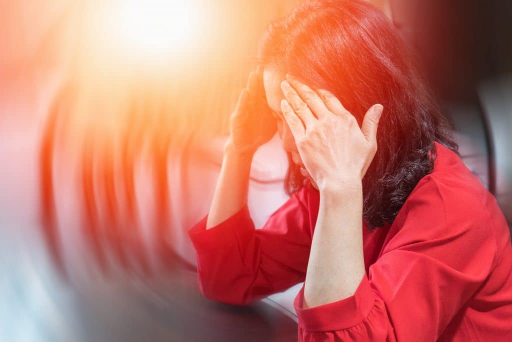 Woman holding her head and resting her fingertips on her forehead in a haze, used to explain vertigo