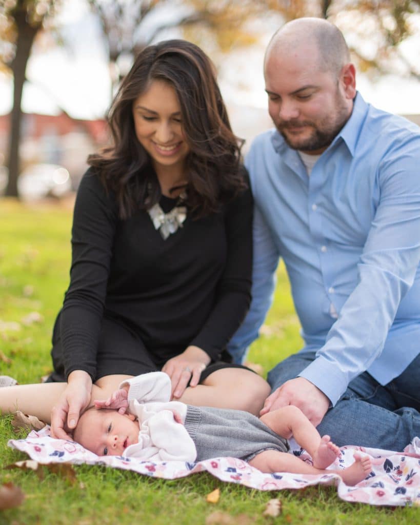 Midlothian residents Daniel and Alyssa McCoy looking at their baby Heidi on a blanket on top of a grassy area