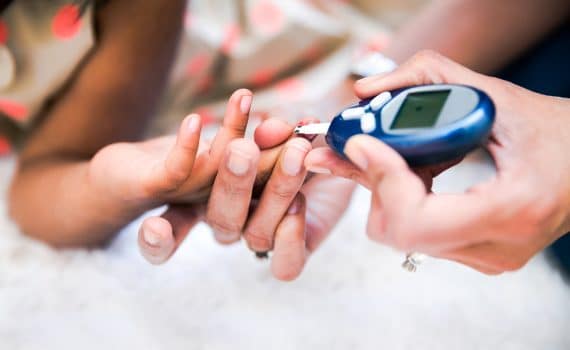 Mother is checking her daughters' diabetes by monitoring blood glucose