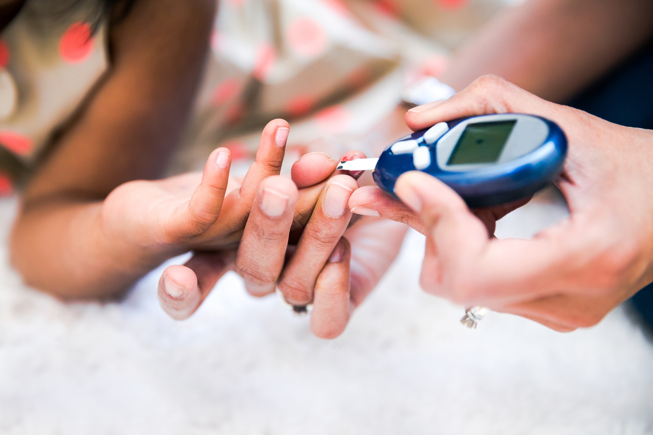 Mother is checking her daughters' diabetes by monitoring blood glucose
